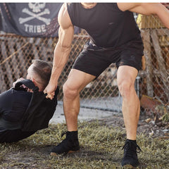 Strong man wearing black gear helping another man in outdoor tough training with GORUCK rucking equipment