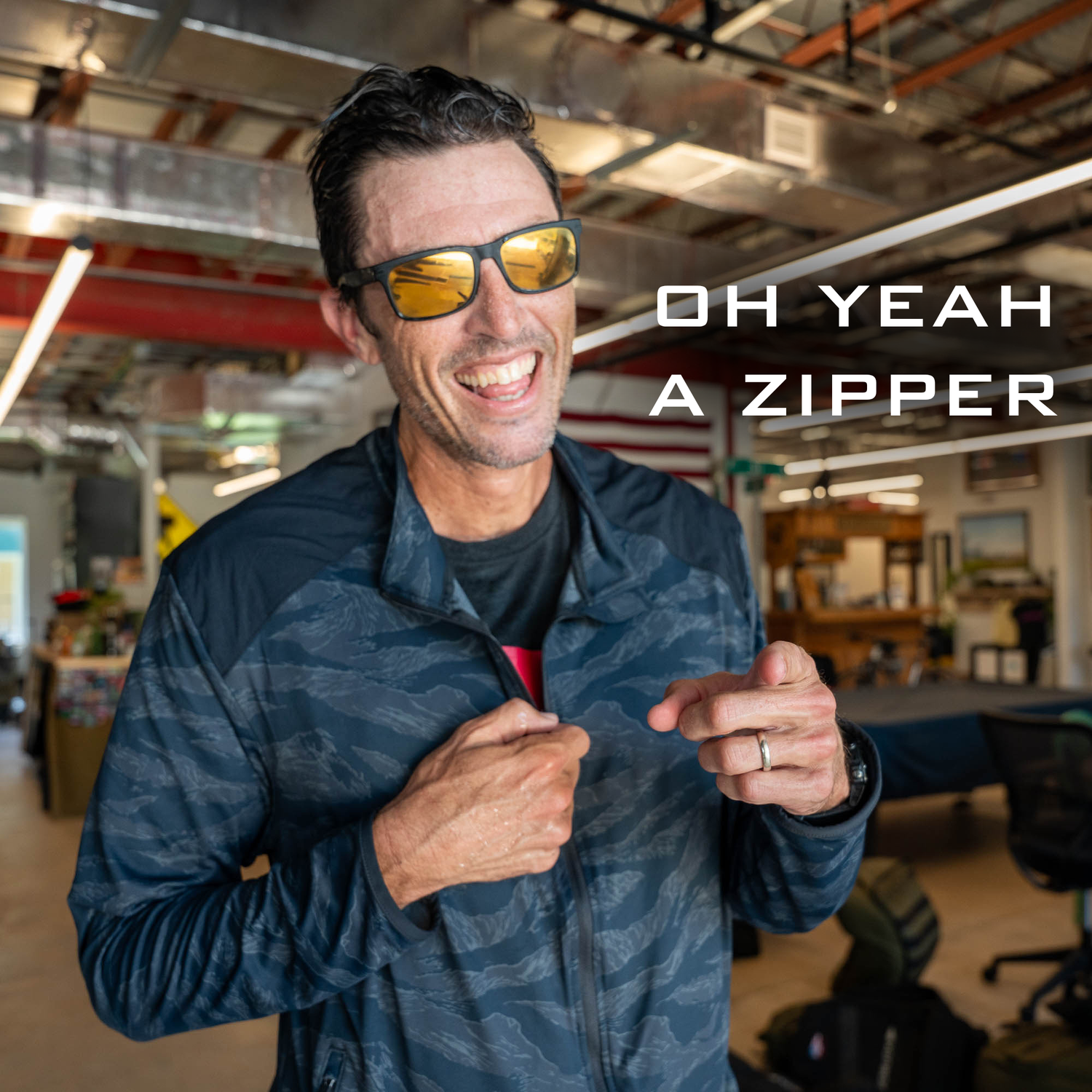Smiling man in sunglasses points to his jacket zipper; text reads 