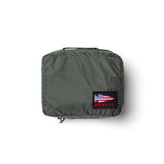 The olive green GORUCK Packing Cube is made from durable 200D nylon, features a handle and an American flag patch on the front—ideal for travel organization or use as packing cubes.