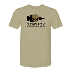 The Selection Jax Beach 2025 - Tri-Blend tee in tan features a black skull and spearhead logo with "GORUCK JAX BEACH 2025" on the front, celebrating grit and resilience. Made from premium tri-blend fabric for exceptional comfort.