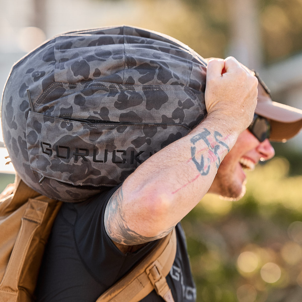 Man carrying a Sand Medicine Ball on his shoulder, ideal for portable training or your home gym, wearing sunglasses and a cap.
