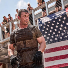 Man wearing GORUCK rucking gear and gloves, soaked in water, with American flag in background