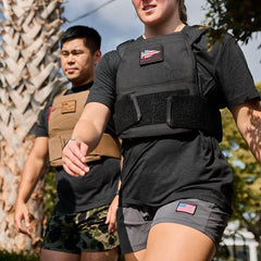Two people rucking outdoors wearing GORUCK weighted vests and athletic gear.