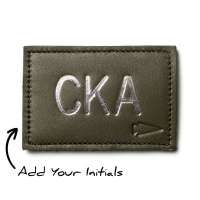 Silver "CKA" lettering with an arrow design on a green patch offers easy customization with the caption "Add Your Initials," under the product name "Patch - Custom Leather Monogram.