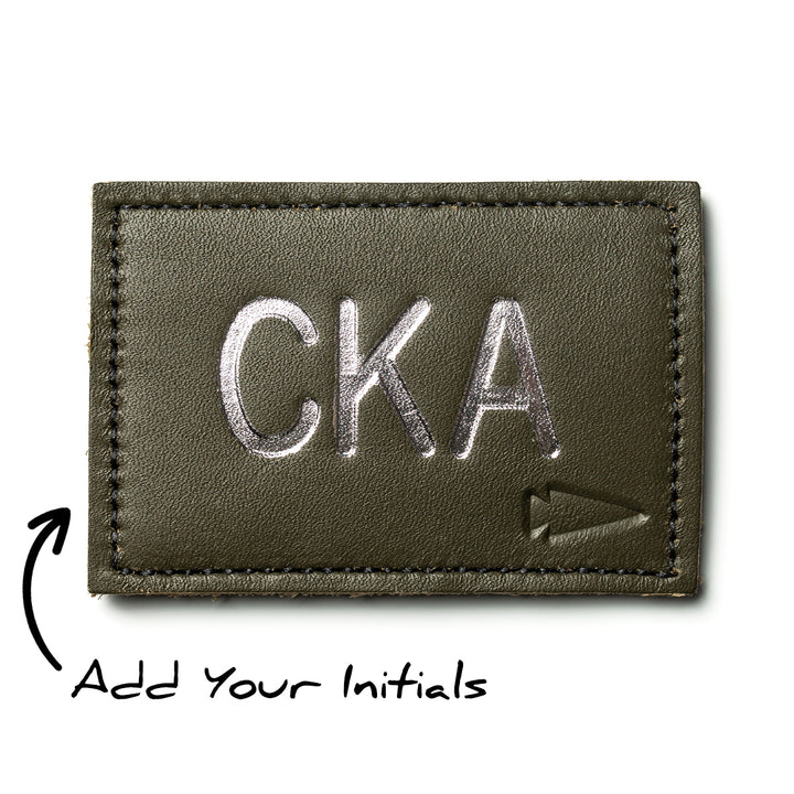 Silver "CKA" lettering with an arrow design on a green patch offers easy customization with the caption "Add Your Initials," under the product name "Patch - Custom Leather Monogram.
