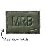 The Patch - Custom Leather Monogram features a green leather design embossed with "MRB" and a small arrow. Personalize it by adding your initials for a unique, custom leather patch tailored just for you.