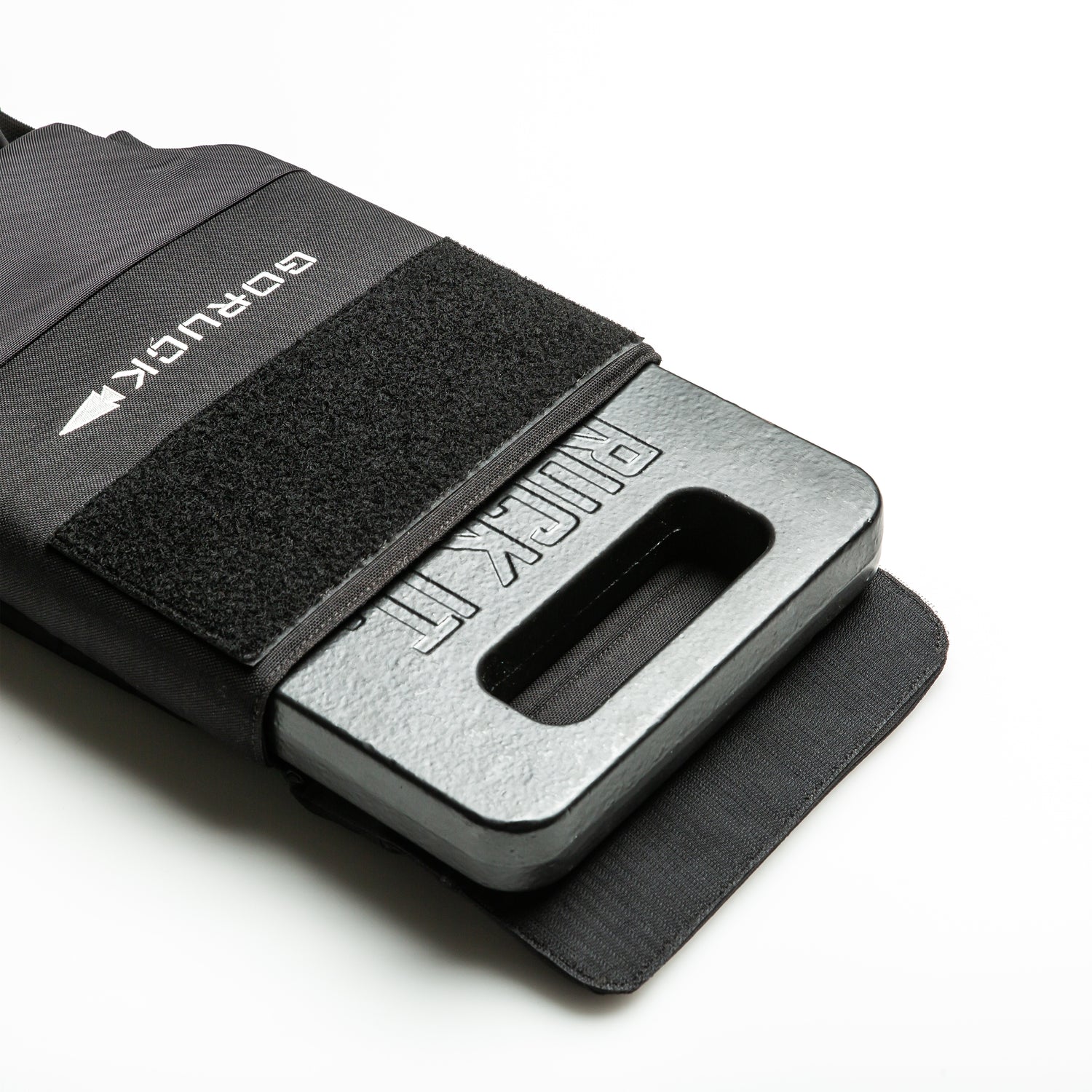 An RPC 3.0 + 10lb Ruck Sandplate is partially inserted into a black sleeve with a Velcro strap, designed for weighted training, set against a white background.