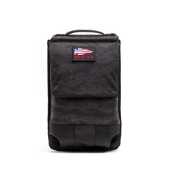 The Ruck Plate Carrier 3.0 is a black rucksack crafted from durable ballistic nylon, featuring a top handle and an American flag patch with "GORUCK" on the front flap.