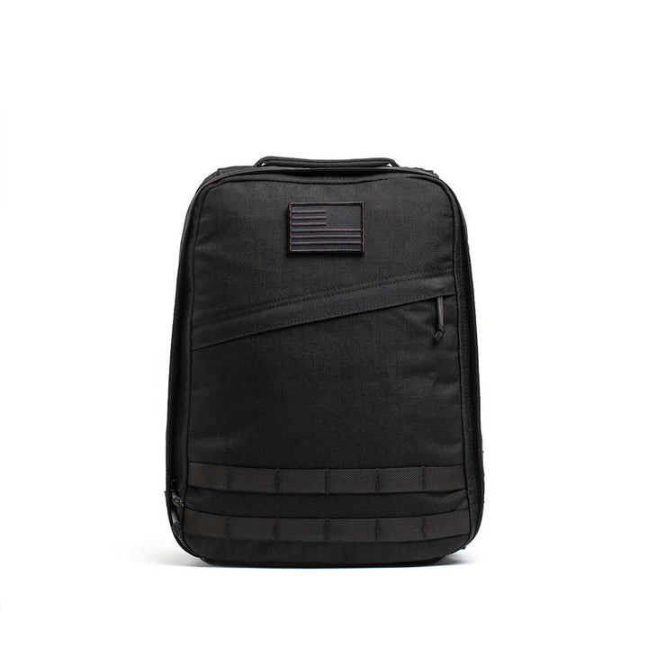 The Radio Ruck USA Throwback backpack features a muted American flag patch, front zipper pocket, horizontal webbing accents, and a bombproof laptop compartment inspired by Special Forces durability.