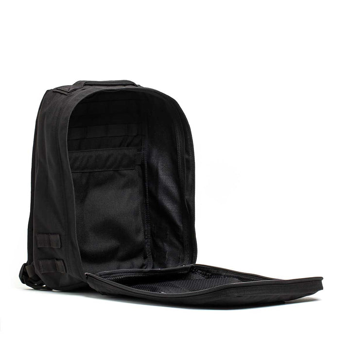The Radio Ruck USA Throwback backpack, shown with its main compartment open, reveals interior pockets, a zippered mesh section, and a bombproof laptop compartment inspired by Special Forces durability.