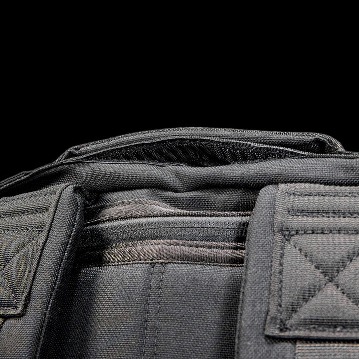 Close-up of the Radio Ruck USA Throwback, a black tactical-inspired backpack with visible stitching and padded shoulder straps, designed for durability and versatility, set against a black background.