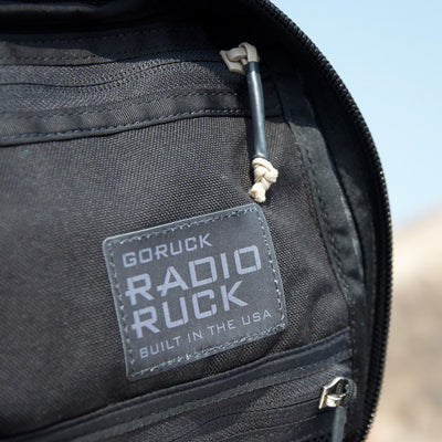 Close-up of a black Radio Ruck USA Throwback backpack with a "Built in the USA" patch, featuring a bombproof laptop compartment inspired by Special Forces durability.
