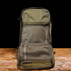 A GORUCK GR2 - Cordura backpack, in olive-green and evoking the style of a Special Forces rucksack, is shown open on a wooden surface against a black background. It includes multiple mesh compartments and pockets for efficient organization. The interior is visible, highlighting its roomy GR2-inspired design.