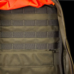 A detailed look inside the GORUCK GR2 backpack showcases its green fabric with a grid-like pattern and a spacious pocket, underscoring its Special Forces quality. The design also includes an orange padded section at the top, highlighting its texture and structure while staying carry-on compliant.