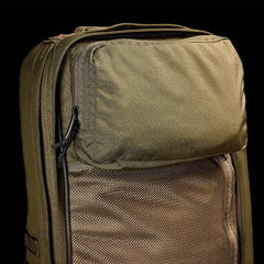 Close-up of a green GR2 - Cordura by GORUCK against a black background. This Special Forces-inspired backpack features a large front pocket with a zipper, mesh panel detailing, and appears to have durable fabric.