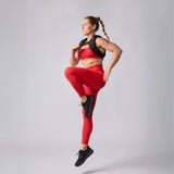 Woman in red athletic wear and weighted vest performing fitness move for GORUCK rucking gear