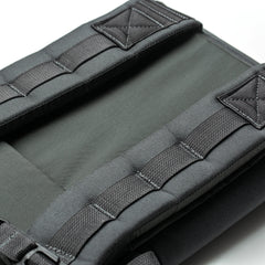 Close-up of RPC 3.0 + 10lb Ruck Sandplate's padded black backpack straps with reinforced stitching and lumbar support on a light background.