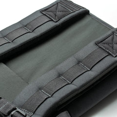 Close-up of padded, dark gray shoulder straps and stitching on the RPC 3.0 + 10lb Ruck Sandplate backpack against a white background.