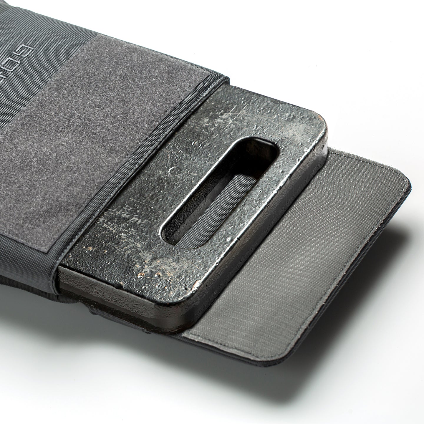 A black RPC 3.0 + 10lb Ruck Sandplate is partially inserted into an open gray pouch, ready for use with a Ruck Plate Carrier or weighted training vest.