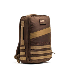 The Rucker 4.0 is a brown GORUCK rucking backpack with tan accents, front and side MOLLE webbing, an American flag patch, and a design compatible with ruck plates.
