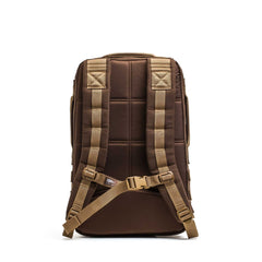 The Rucker 4.0 in brown and tan is shown from the back, featuring padded straps, a chest buckle, and compatibility with ruck plates.