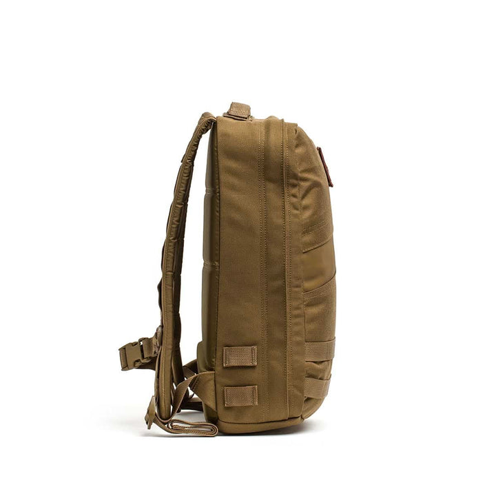 Side view of the Rucker 4.0 backpack in brown featuring padded straps, multiple stitched loops, and space for Ruck Plates, displayed on a white background.