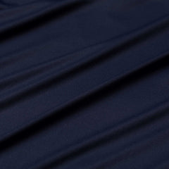 Close-up of dark blue, slightly wrinkled fabric from the Men's Long Sleeve Rucking Polo, highlighted by soft diagonal folds—crafted in Merino wool for moisture-wicking and odor resistance.