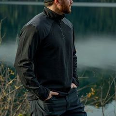 Man wearing GORUCK black quarter-zip rucking jacket outdoors near a lake