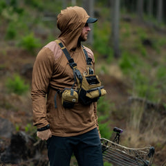 Man outdoors wearing GORUCK rucking gear, brown hoodie, tactical chest pack in forest