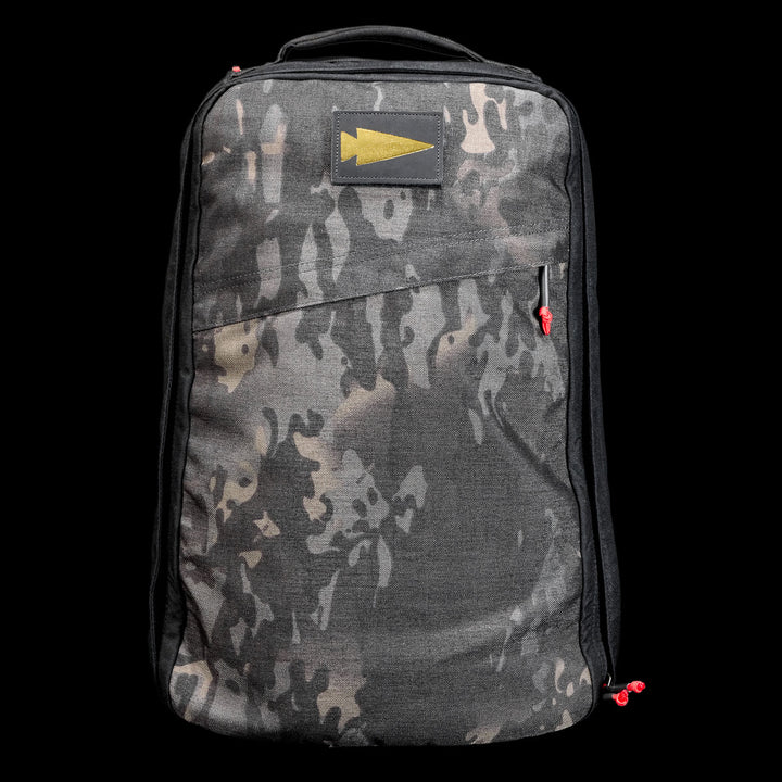 The GR1 Shooter 26L - Built by Scars is a camo-patterned backpack crafted from rugged CORDURA®, with a yellow arrow patch and red zipper pulls, shown on a black background.