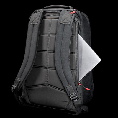 The GR1 Shooter 26L - Built by Scars is a black CORDURA® backpack with padded straps and a laptop partially visible in the side zippered pocket.