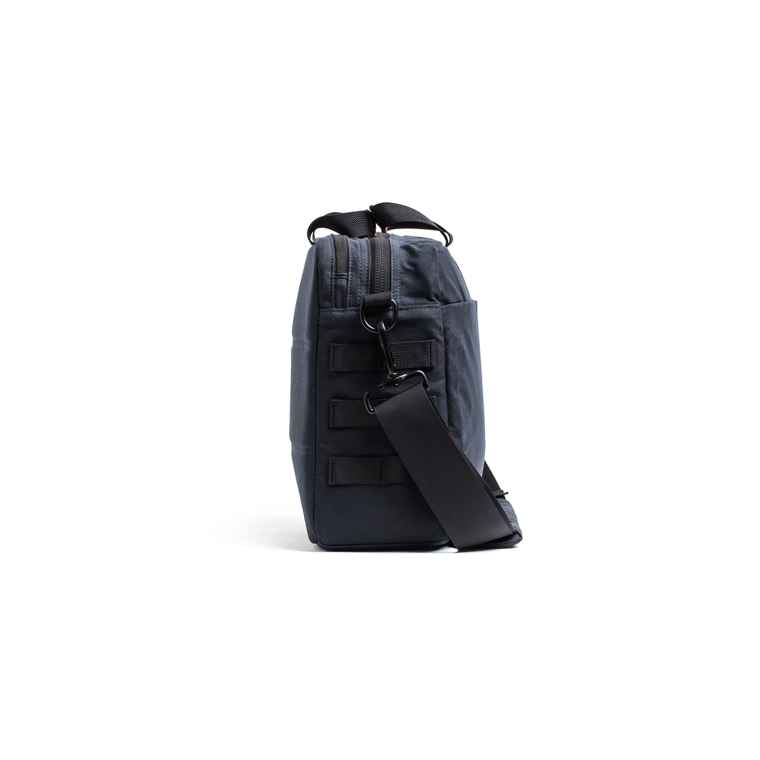 Side view of the Shoulder Bag - Waxed Canvas in dark gray, featuring a black strap for asymmetrical carry, displayed against a white background.