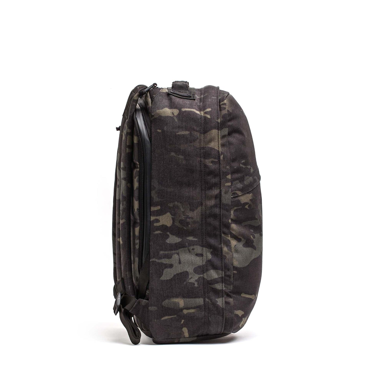 Side view of the GR1 USA Slick - Ballistic Nylon Cordura backpack in black and gray camouflage with shoulder straps, featuring a bombproof laptop compartment, against a white background.