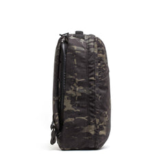 Side view of a black and grey camouflage GR1 USA Slick - Ballistic Nylon Cordura backpack with a bombproof laptop compartment, set against a white background.