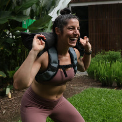 Woman rucking outdoors with GORUCK backpack, smiling during fitness training