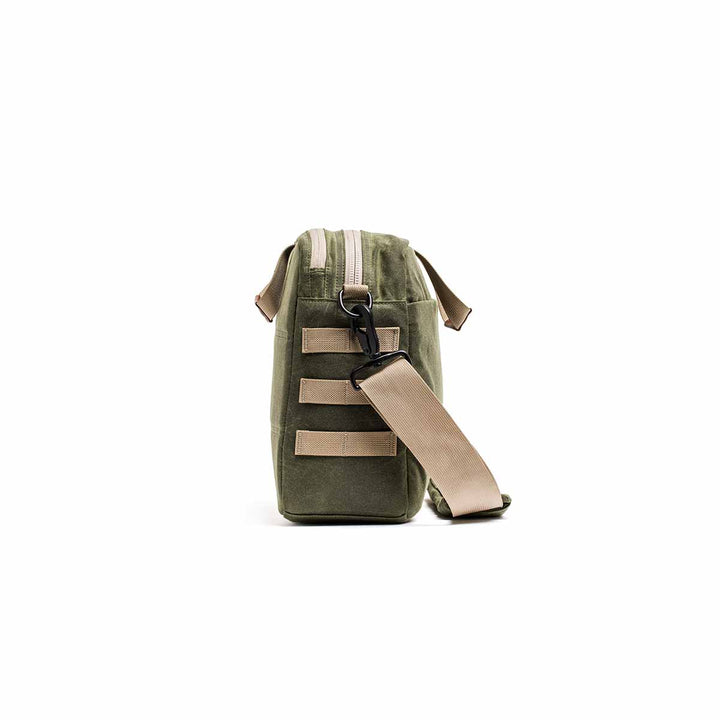 Side view of the Shoulder Bag - Waxed Canvas in olive green, featuring a beige strap and zipper for comfortable asymmetrical carrying, isolated on a white background.