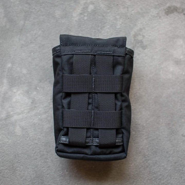 The GORUCK Simple Side Pocket, equipped with MOLLE webbing and horizontal straps, rests on a gray, textured surface.