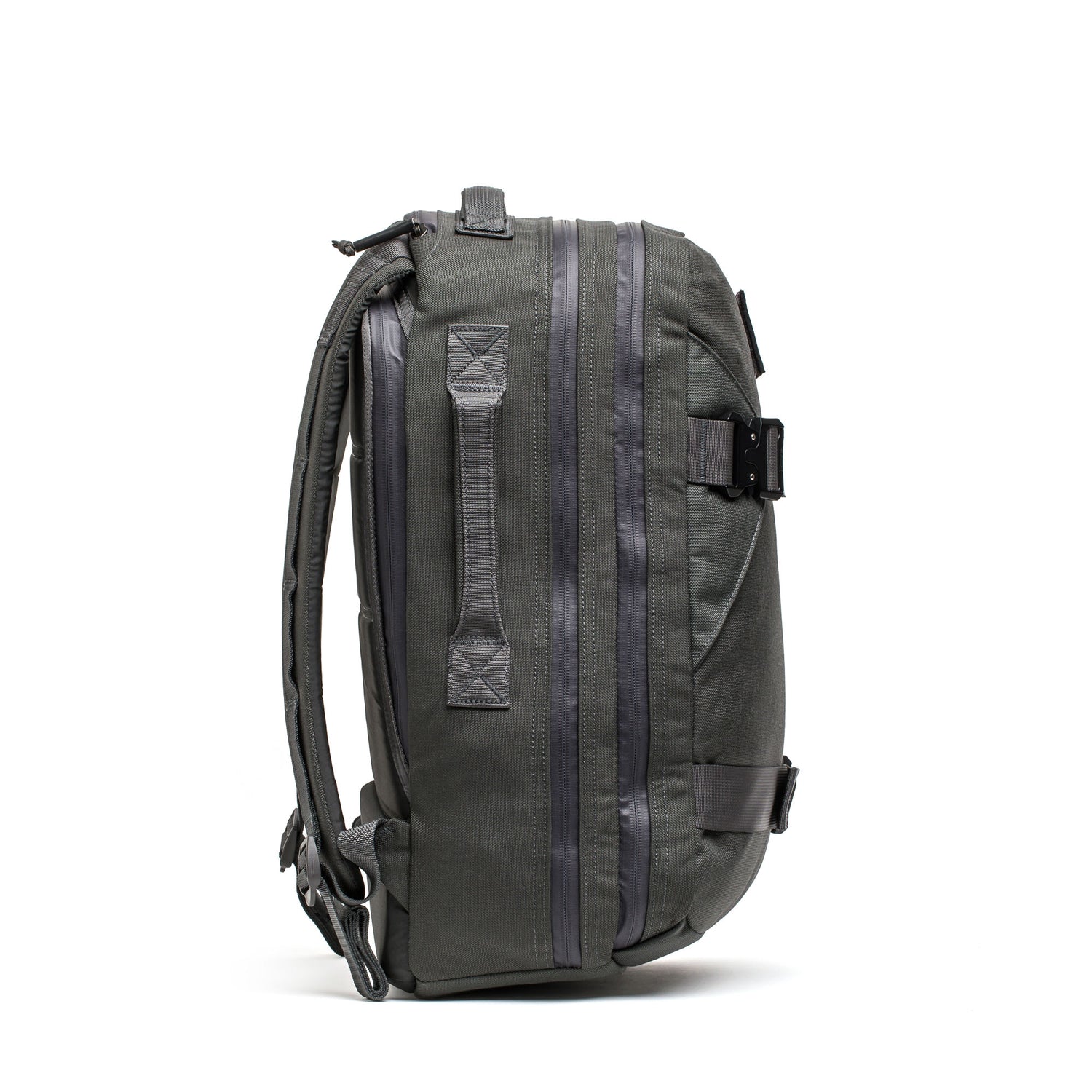 Side view of the Skate Ruck, a dark gray EDC bag with zippers, handles, adjustable shoulder straps, and a bombproof laptop compartment, shown on a white background.