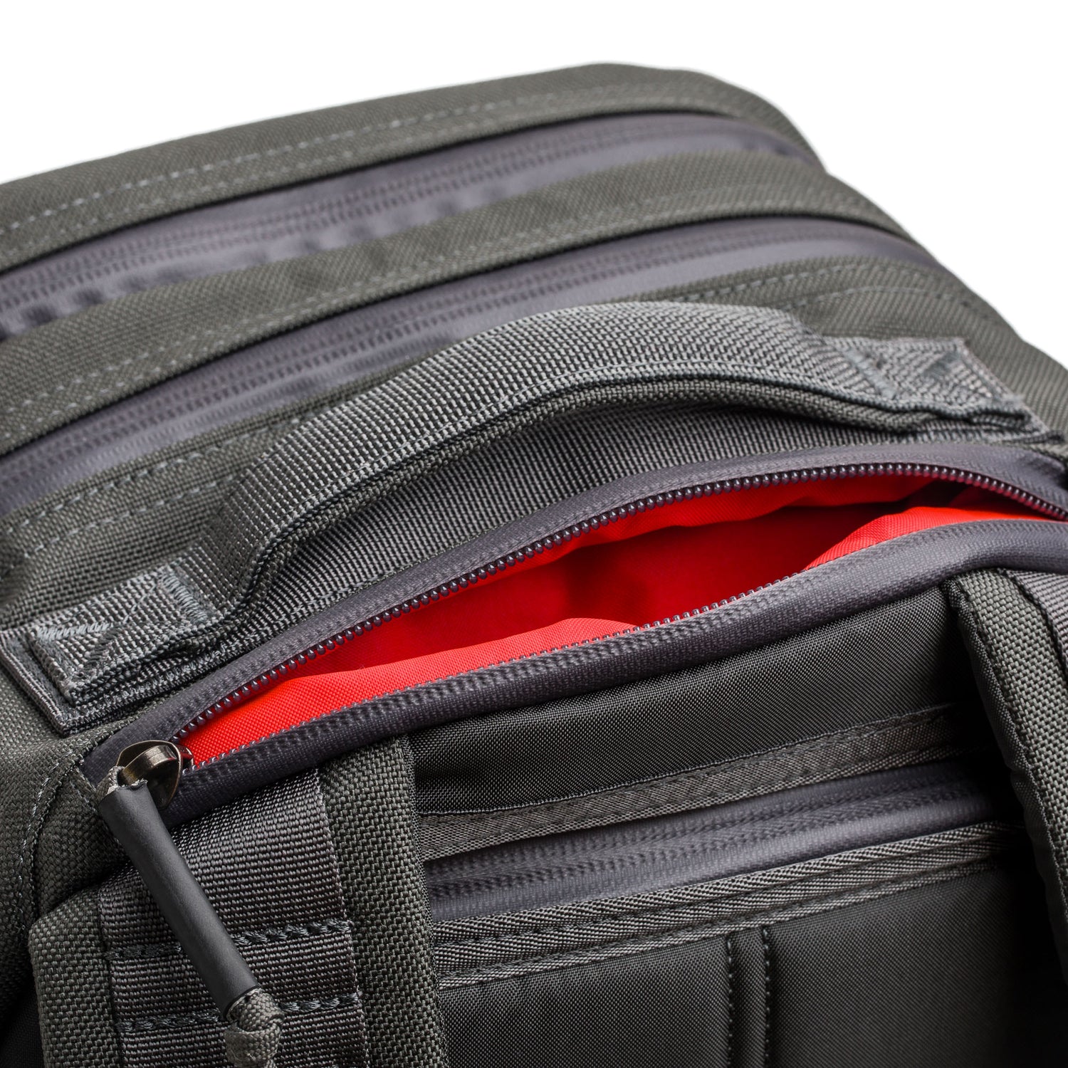 Close-up of the gray Skate Ruck, showcasing its partially opened zipper with a bright red interior and an ultra-durable laptop compartment.