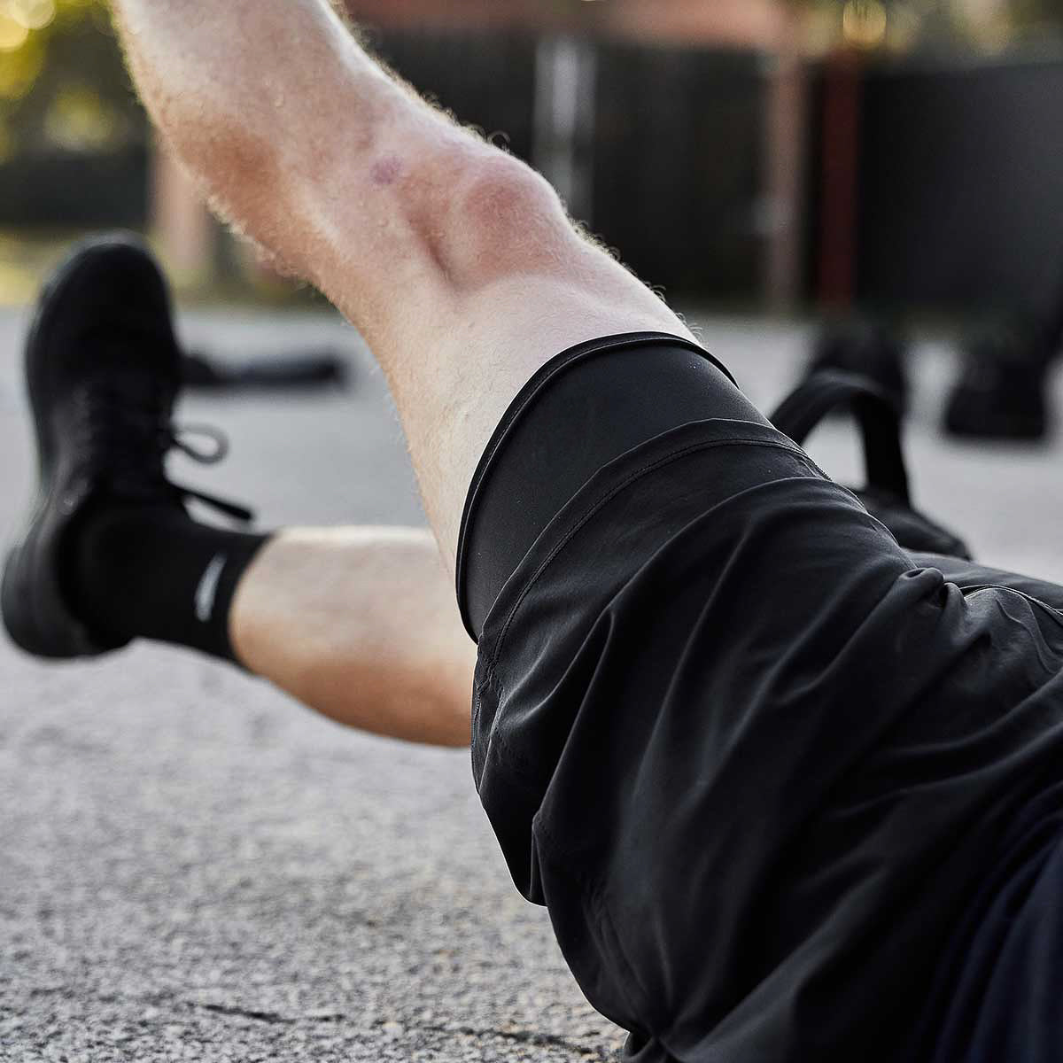 A person exercises outdoors in Performance Briefs and shoes, lifting one knee while enjoying the comfort and breathability of the material.