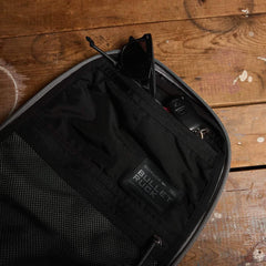 Open black GORUCK Bullet Ruck 15L organizer pouch with sunglasses and keys on wooden surface