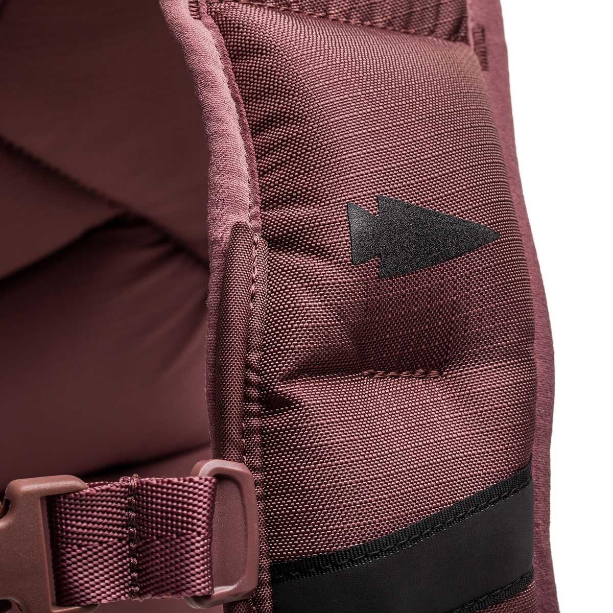 Close-up of a maroon strap with a black arrow symbol and plastic buckle, designed for the Spy Ruck | Women's Weighted Vest.