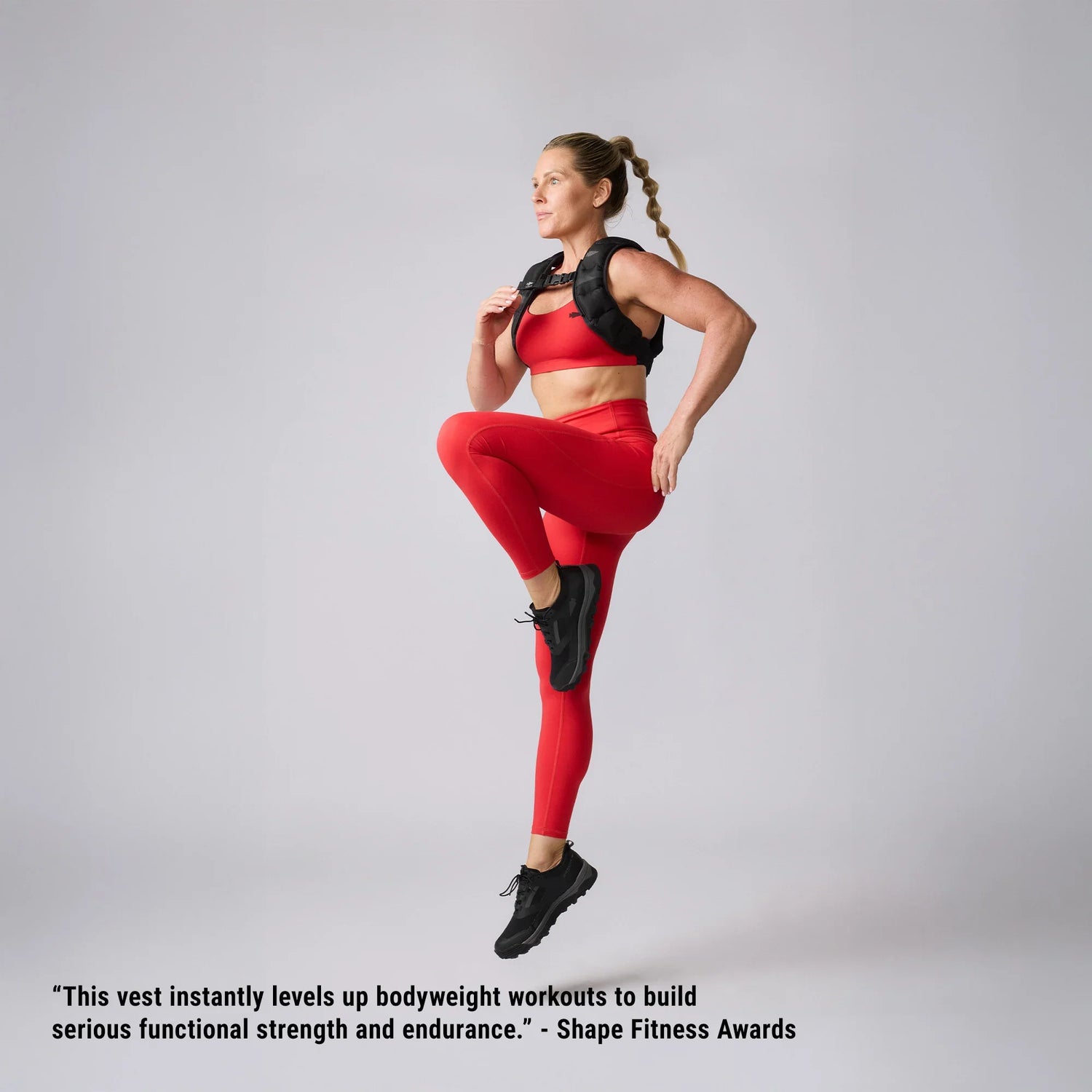 Woman in red workout gear performing high knee exercise wearing black GORUCK training vest.
