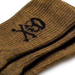 Tribe Merino Challenge Socks - Crew: brown, close-up view shows soft merino wool with a black skull and crossbones design. Includes a lifetime guarantee for lasting comfort and durability.