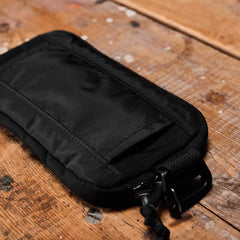 Black GORUCK sternum pouch with zipper and attachment loop on wooden surface
