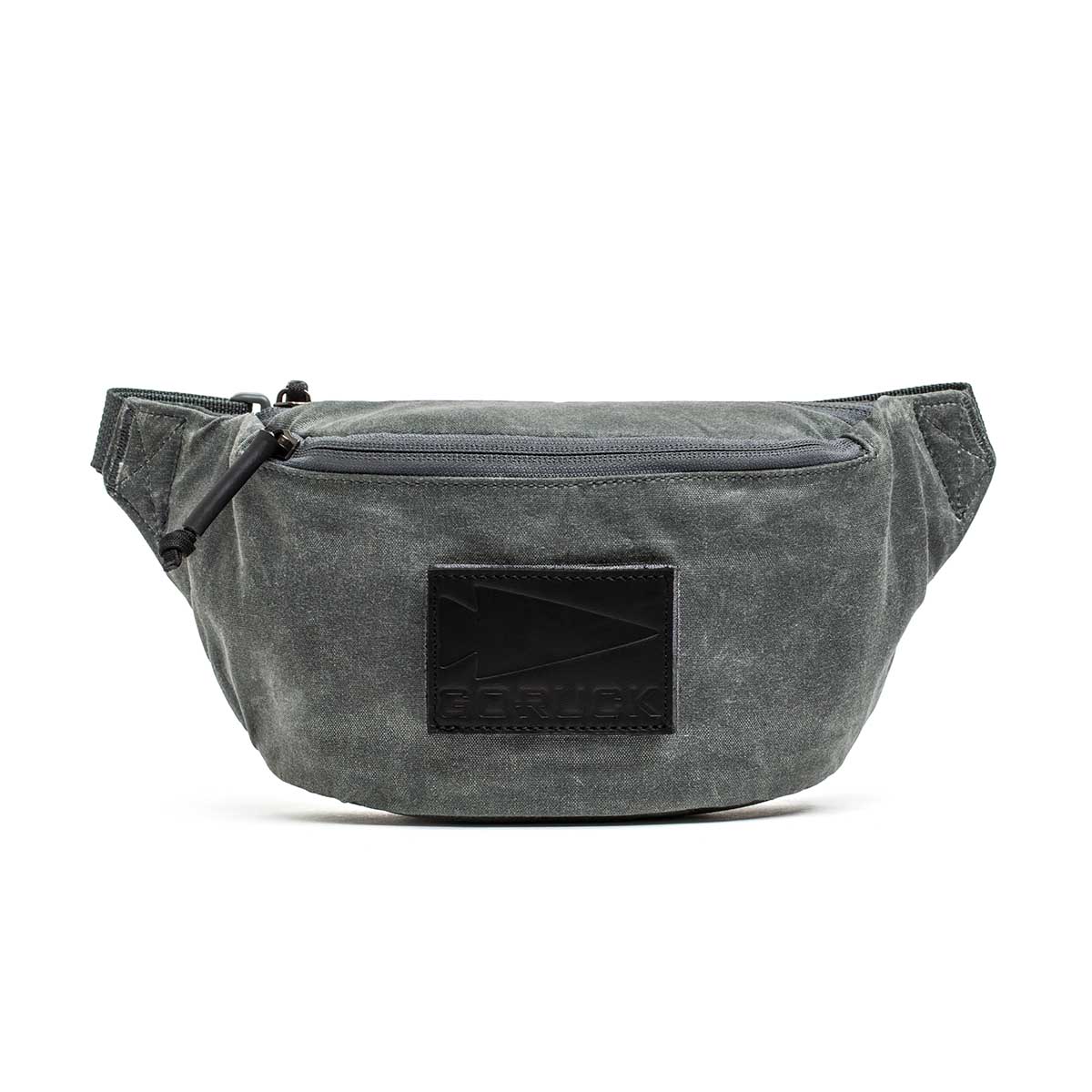 The Tactical Fanny Pack - Waxed Canvas is a gray waist pack with a front zipper featuring silent pulls and a black rectangular patch on the front.