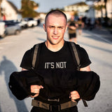 Teen boy rucking outdoors with GORUCK gear, carrying a weighted sandbag, strength training