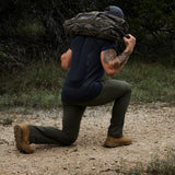 Man rucking outdoors with camouflage sandbag, wearing GORUCK gear on a trail