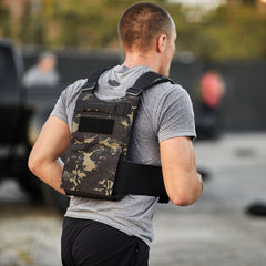 A man runs outdoors wearing a gray t-shirt and the Training Weight Vest 2.0, loaded with ruck plates.