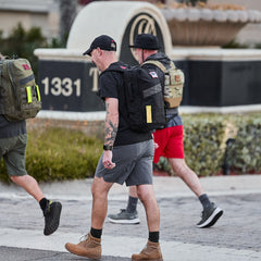 Three people in casual clothes walk past a sign with the number 1331, each wearing the Subtle Spearhead Tee - Tri-Blend, inspired by Special Forces and crafted for ultimate comfort.